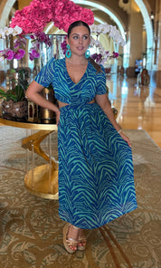 Woman in a blue dress sitting in a luxurious interior setting with floral decorations.