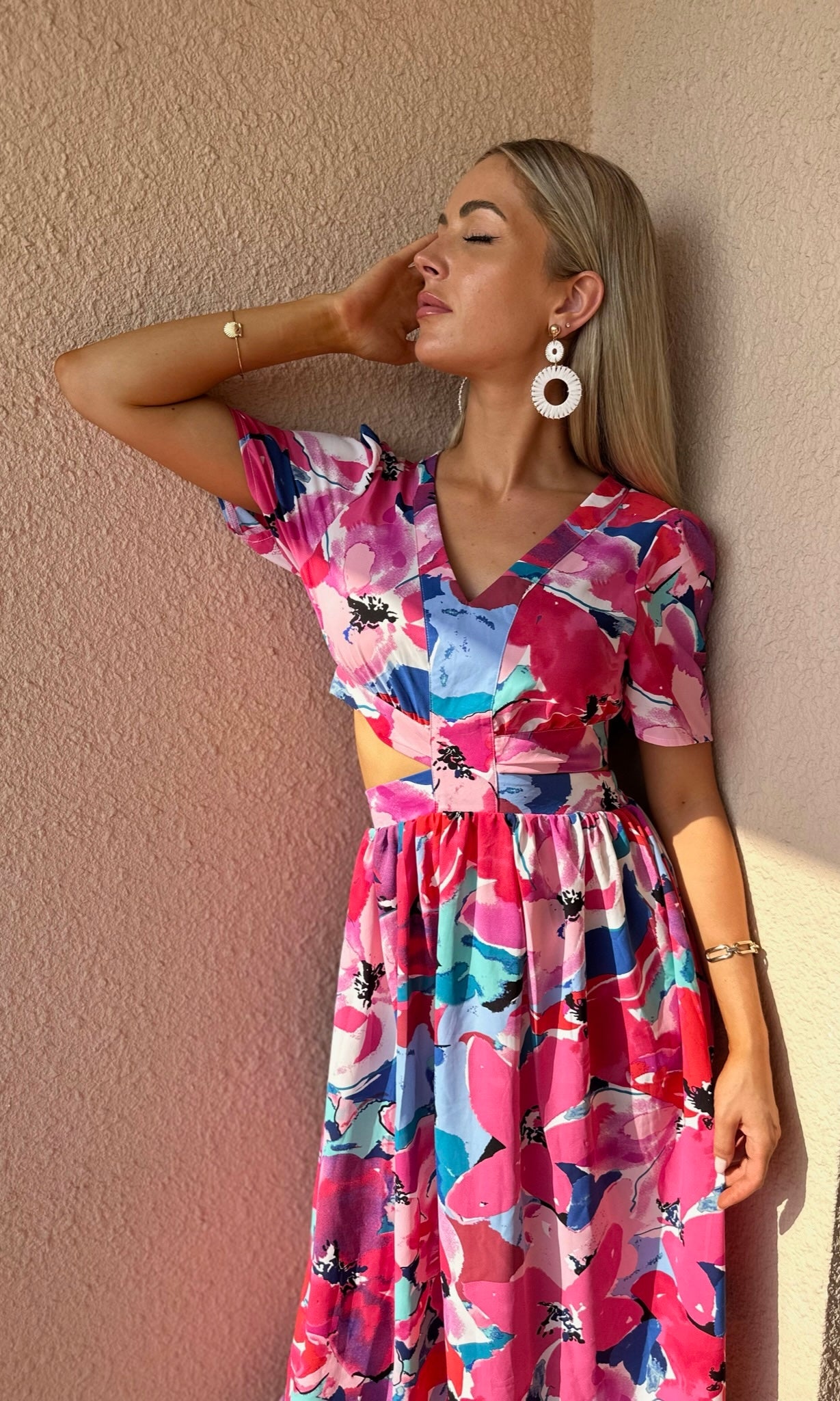 Woman wearing a colorful floral dress against a beige wall