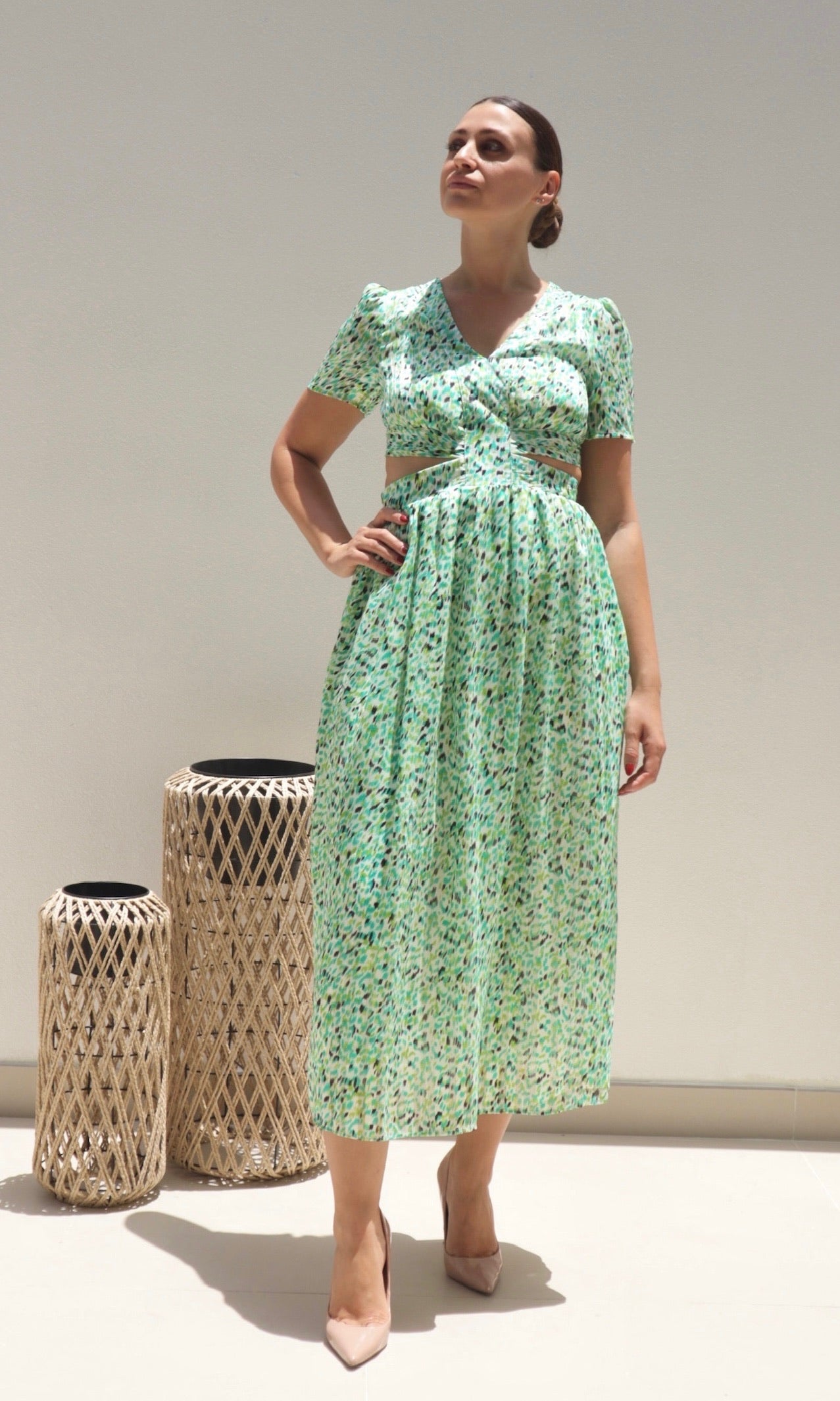 A woman models a green maxi dress with a smudged leopard print design, featuring short sleeves, a tie back, and cut-out sides.